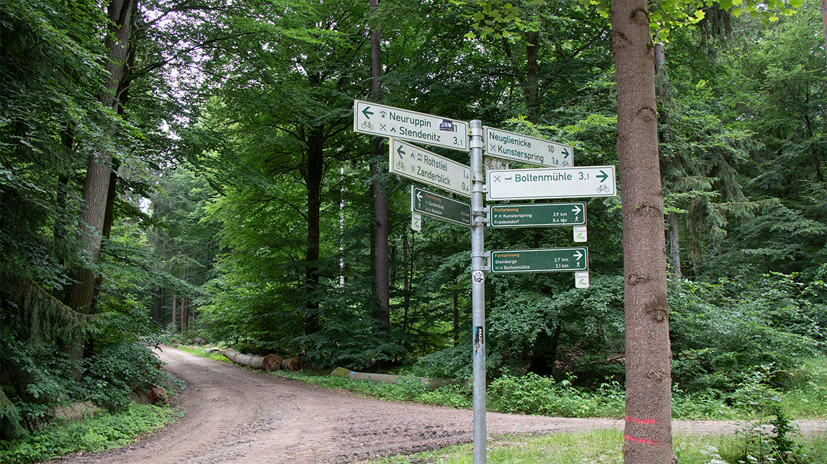 Wegweiser bei 53.0218267, 12.7893383 mit Richtungen nach Neuglienicke, Kunsterspring, Boltenmühle, Neuruppin, Stendenitz, Rottstiel und Zanderblick.
