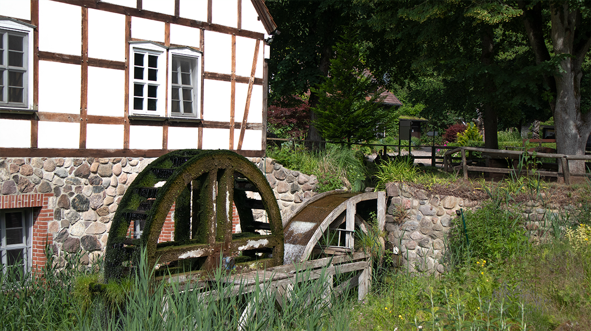 Altes Mühlrad der Boltenmühle bei 53.0372067, 12.8039617 in der Ruppiner Schweiz vor dem historischen Fachwerkgebäude.